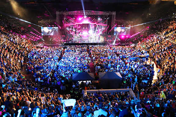 A large crowd of people are gathered in a stadium for a concert.