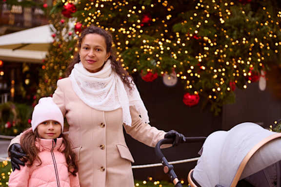 A woman and a girl are standing in front of a Christmas tree.