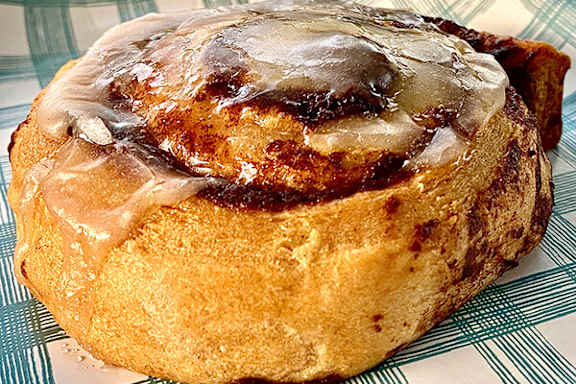 A cinnamon roll with a shiny glaze on top.