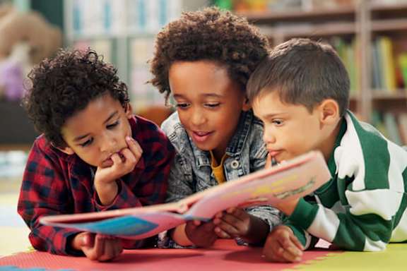 Three children are reading a book together.