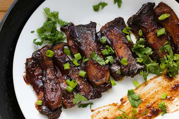A plate of cooked meat garnished with green onions and parsley.