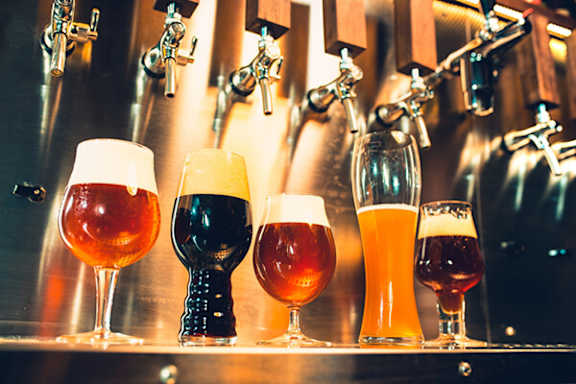 A row of beer glasses are lined up on a bar.