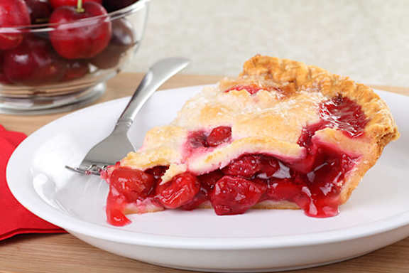 A slice of cherry pie on a plate with a fork.
