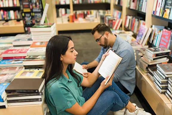 A man and a woman are reading books in a bookstore.