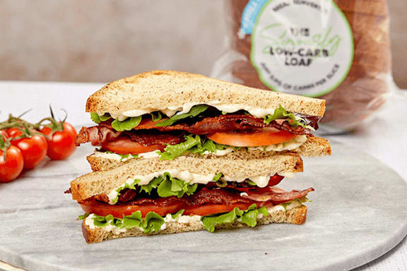 A sandwich with bacon, lettuce, and tomato slices on a plate.
