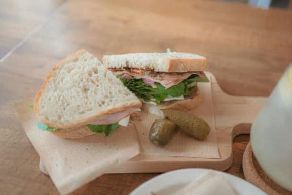a sandwich on a cutting board with pickles