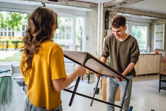 A man and a woman are moving furniture in a room.