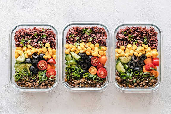 Three containers of food with rice, beans, vegetables, and chickpeas.