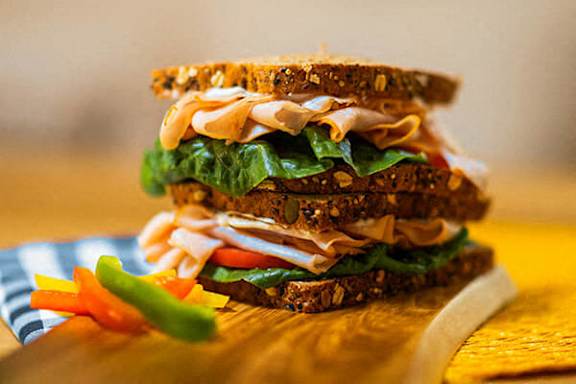 A sandwich with lettuce, tomato, and turkey on whole grain bread.