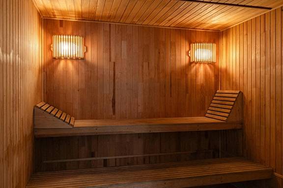 A wooden sauna with benches and lights on the wall.