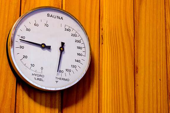 A Sauna thermometer on a wooden surface.