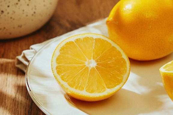 A half of a lemon is on a white plate.