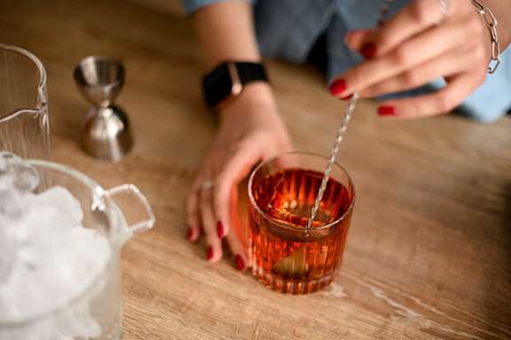 A person is pouring a red liquid into a glass.