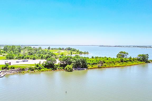 A serene landscape with a body of water, greenery, and a clear sky.