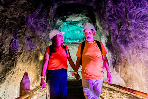 A man and a woman are walking hand in hand in a cave.