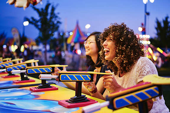 Two women playing a game at an amusement park.