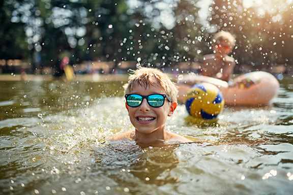 A person is swimming in a pool with a yellow and blue ball nearby.