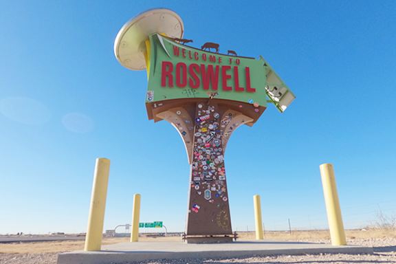 A sign welcoming people to Roswell with a large hat on top.