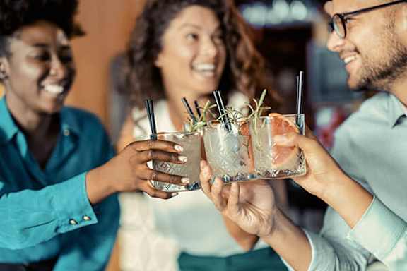 Three people toasting with drinks in their hands.