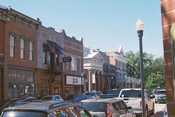 A street view of a town with cars parked on the side of the road.