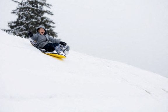a boy riding a snowboard down a snow covered slope