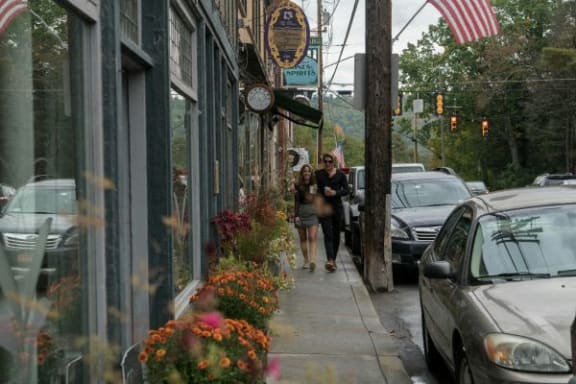 two people walking down the sidewalk on a city street