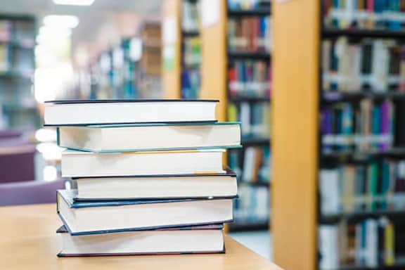 A stack of books is on a table in a library.