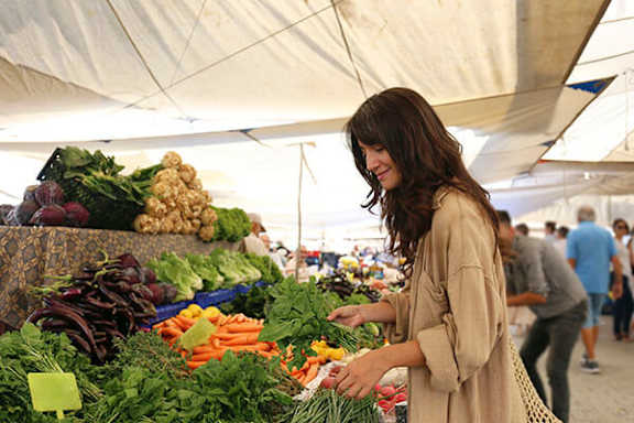 A woman is shopping for vegetables at a market.