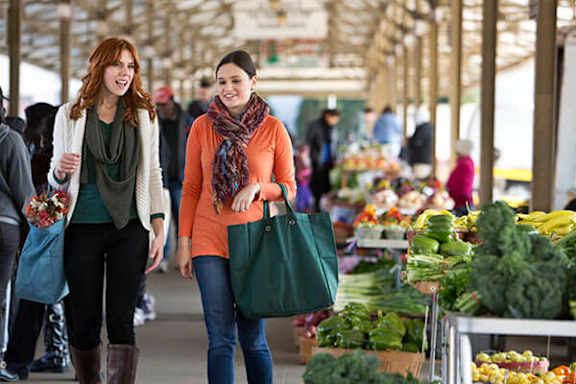 Two women shopping for vegetables at a market.