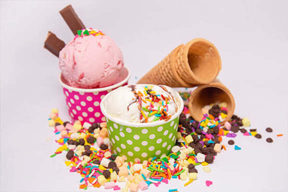 Ice cream cones and cups with sprinkles on a white background.
