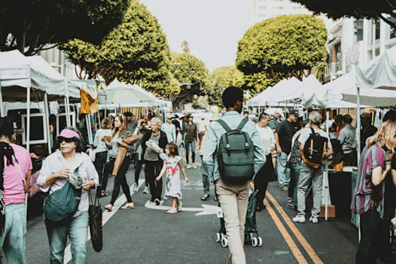 A busy street market with people walking and shopping.