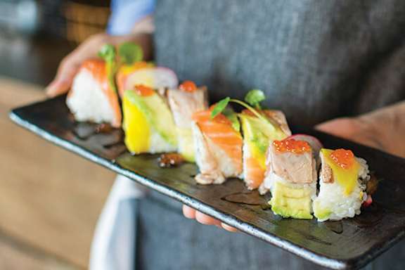 A person holding a tray of sushi.