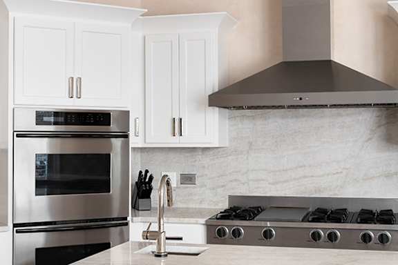 A modern kitchen with a stainless steel oven and a marble backsplash.