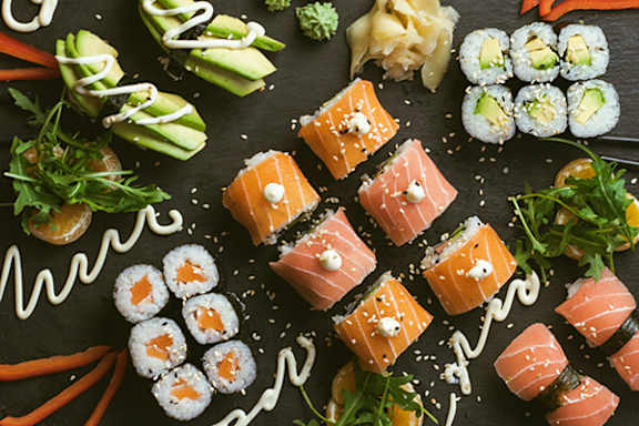 A variety of sushi pieces are arranged on a black surface.