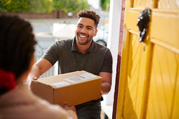 A delivery man is handing over a package to a woman.
