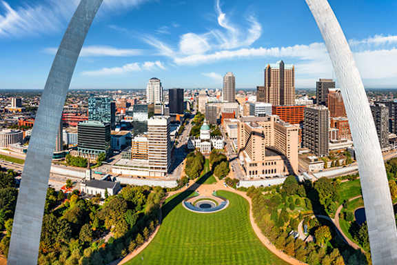 A cityscape with a large arch in the foreground.