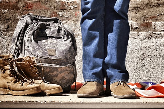 A pair of brown shoes stand next to a bag with the word "AUST" on it.