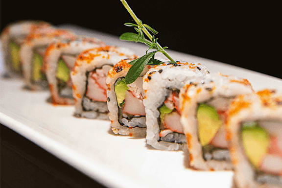 A plate of sushi rolls with a sprig of rosemary on top.