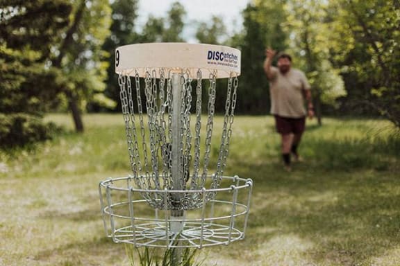 a man standing in a field with a frisbee disc golf goal
