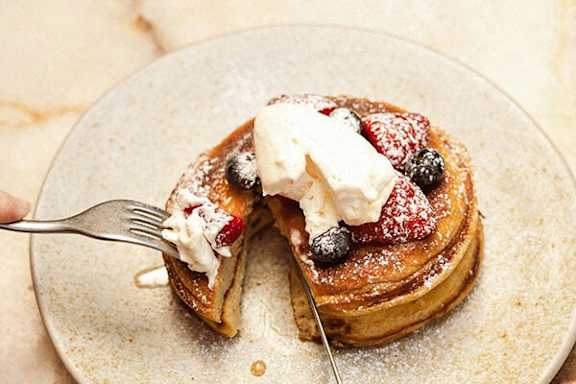 A plate of pancakes topped with whipped cream and berries.