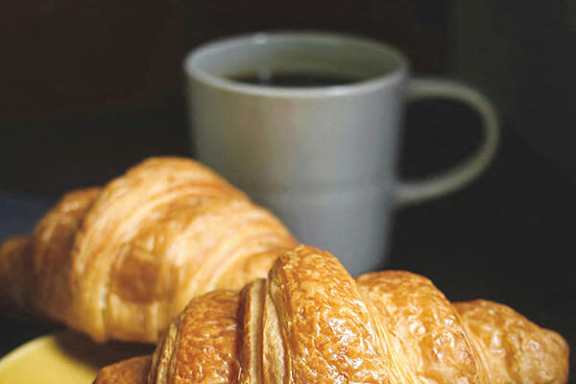 Two croissants and a cup of coffee on a table.