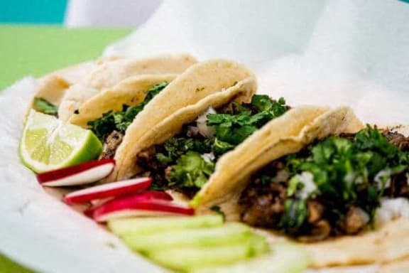 a plate of tacos and pickles on a table