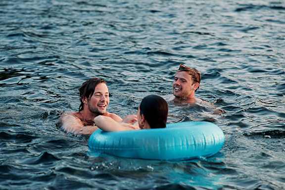 A group of people are swimming in the ocean with an inflatable ring.