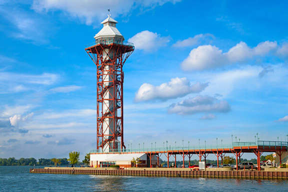 A red lighthouse stands on a pier over a body of water.