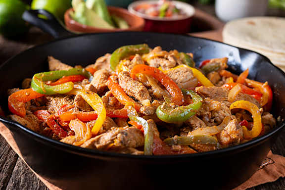 A skillet of meat and sliced bell peppers.