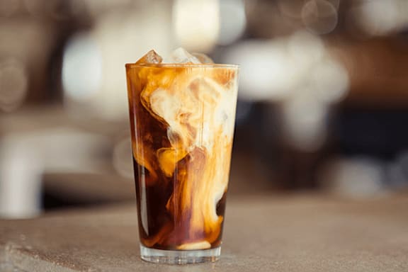 A glass of iced coffee with ice cubes in it.