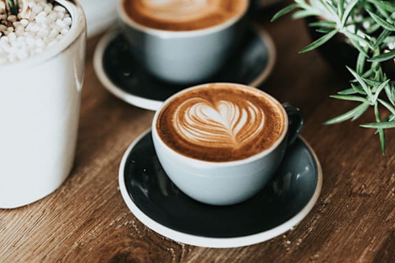 Two cups of coffee with latte art on a wooden table.
