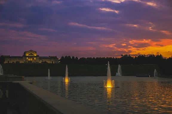 a group of sailboats on a lake at sunset with a palace in the background