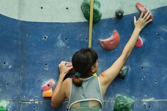athletic person is climbing a rock climbing wall