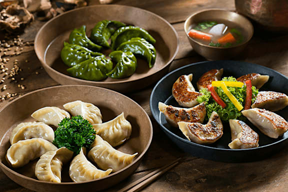 A variety of Asian dishes are displayed on a wooden table.